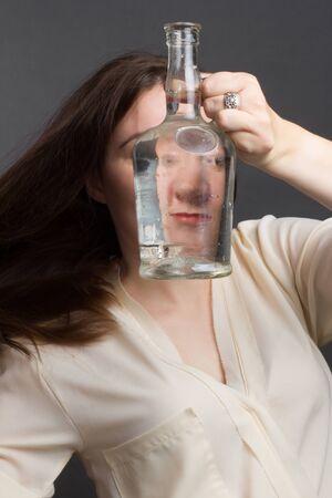 portrait of woman in Studio, in the brown hat and leather gloves, Looking Through a water bottle....