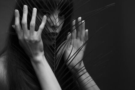 black and white portrait of a young woman with leaf palms. Studio photoの写真素材