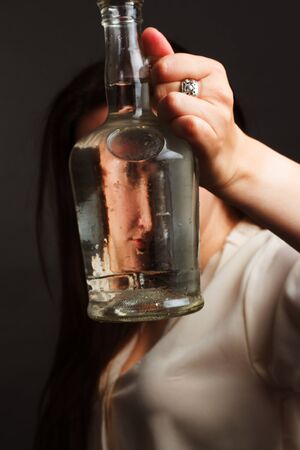 portrait of woman in Studio, in the brown hat and leather gloves, Looking Through a water bottle. with Funny Distortedの写真素材