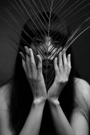black and white portrait of a young woman with leaf palms. Studio photoの写真素材