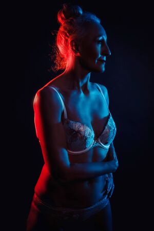 Portrait old woman in colorful bright lights. blue and red. in lingerieの写真素材