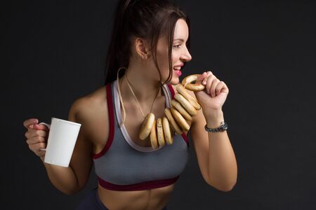 Young Fitness woman in training topic there are bagels with tea. The concept of a wrong sport power supplyの写真素材