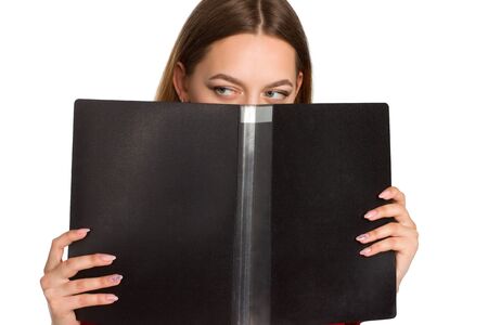 A young business woman against a white background isolated. hiding behind an office folderの写真素材