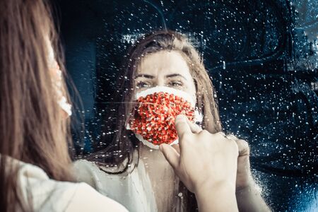 Woman in protective medical mask with rhinestones. Looking in the mirror.