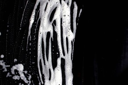 The texture of the soap foam stains marks on a black background. The concept of cleaning, and...