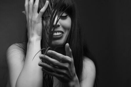 black and white portrait of a young woman with leaf palms. Studio photoの写真素材