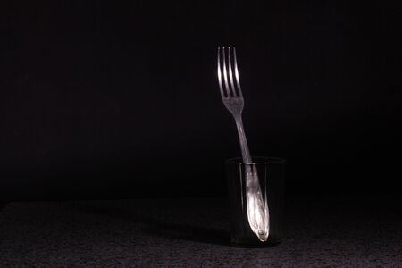 fork in a faceted glass on a black background. Studio concept photographyの写真素材