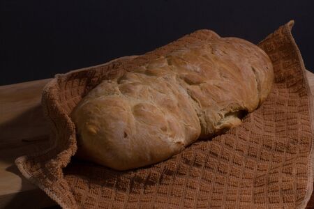 Homemade bread on a brown cloth towel on a wooden cutting Board. Healthy food, diet and home cooking
