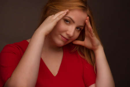 Studio portrait of an overweight young woman with light hair on a black background