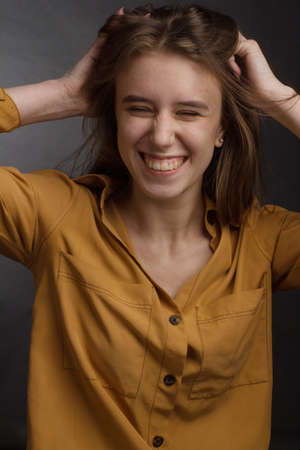 Studio portrait of a young girl with long hair on black background. she holds her head with her hand...