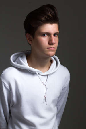 a boy in a white hoodie. Studio portrait on a black backgroundの写真素材