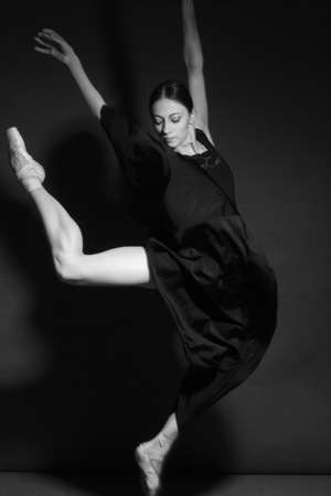 black and white dramatic vintage portrait of a girl, dancing ballerina in a black bodysuit in the Studio on gray backgroundの写真素材