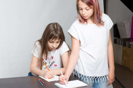 Two young children, Draw with colored pencils in notebooks
