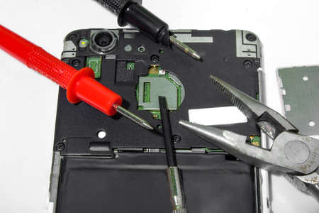 Disassembled old Smartphone, tools :, probes, pliers top view. Theme of phone repair and service.