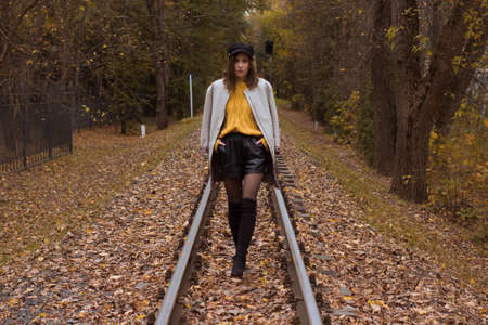 Brunette in autumn Park and autumn leaves. Autumn mood. Yellow, red and green leaves. Goes by rail