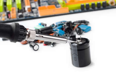 soldering iron on the background of a computer Board and capacitors in soft focus. The concept of...