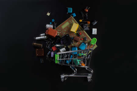 A metal shopping cart filled with radio components. The photo in the dark lighting.
