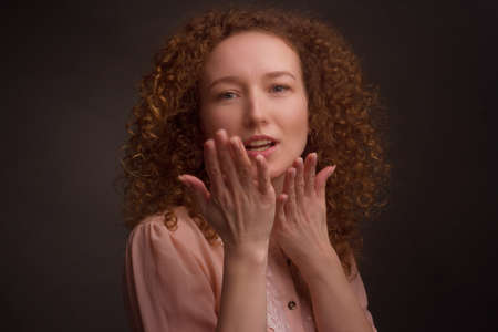 Studio portrait of a young woman with curly hair, blowing kisses