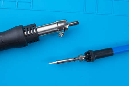 Hot air gun for soldering, and a soldering iron, on the background of a blue