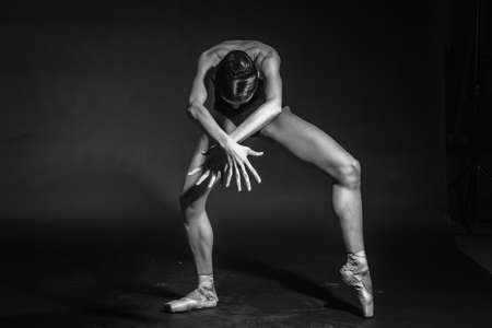black and white dramatic vintage portrait of a girl, dancing ballerina in a black bodysuit in the Studio on gray backgroundの写真素材