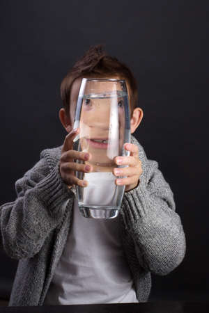 young guy in a white t-shirt looking through a water bottleの写真素材