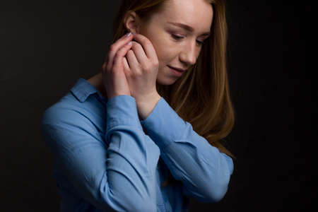 A young woman in a blue blouse, portrait on a black studio background.の写真素材