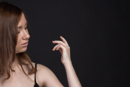Young brown-haired woman, studio photo on a black backgroundの写真素材