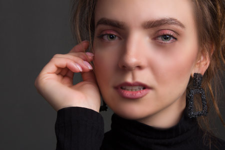Young brunette woman, with gathered hair hairstyles, in the studio on a black background in a black tight-fitting bodysuit.の写真素材