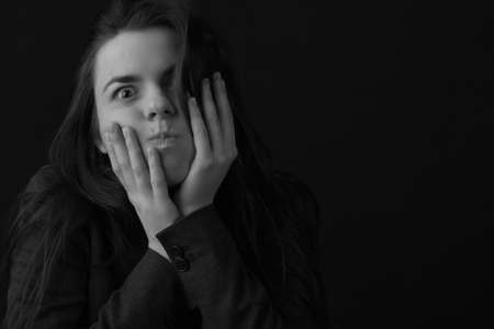 Black and white portrait of a young brunette woman in a studio on a black backgroundの写真素材