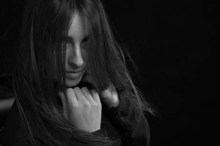Black and white portrait of a young girl with long hair in a studio on a black background
