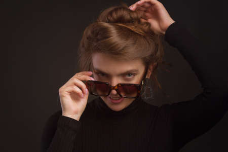 Young brunette woman, with gathered hair hairstyles, in the studio on a black background in a black tight-fitting bodysuit.の写真素材