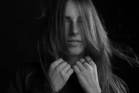 Black and white portrait of a young girl with long hair in a studio on a black background