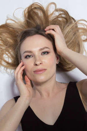 studio portrait of a girl with long blonde hair on a light background, in a black dressの写真素材