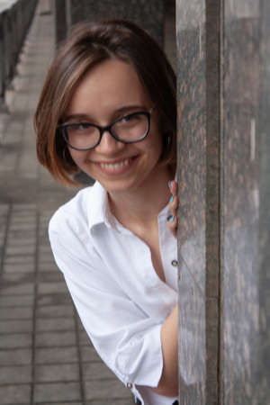 A young woman with short brown hair, wearing a white shirt, with glassesの写真素材