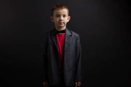 a boy with vitiligo in a red T-shirt, gray jacket, on a black backgroundの写真素材