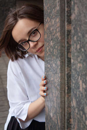 A young woman with short brown hair, wearing a white shirt, with glassesの写真素材