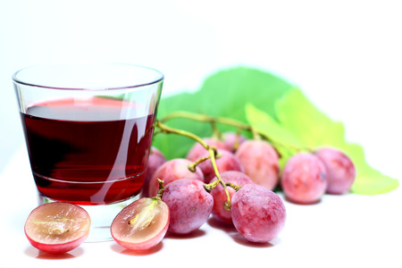 Red rose grapes bunch, glass cup with red natural organic house wine, and autumn grapes leaves isolated on white background.の写真素材