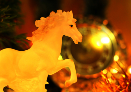Yellow Style New Years Eve celebration background with a glass horse elegant arrangement clock counting down to midnight, New Year`s tree brunch Bokeh light garland backdrops.の写真素材