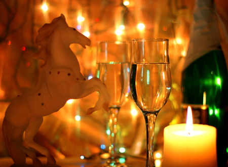 Dark yellow Style New Years Eve celebration background with horse an elegant arrangement with a clock counting down to midnight, flutes and bottle of champagne and party streamers with a candles.の写真素材
