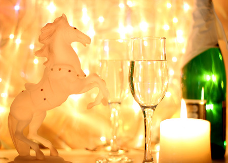 Style New Years Eve celebration background with horse an elegant arrangement with a clock counting down to midnight, flutes and bottle of champagne and party streamers with a candles.の写真素材