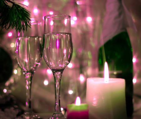 Colorful style New Years Eve celebration background with an elegant arrangement with a clock counting down to midnight, flutes and bottle of champagne and party streamers with a candles.の写真素材