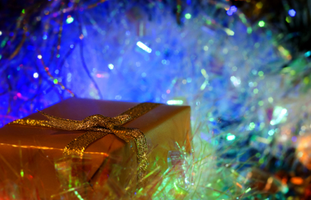 Christmas and New Year`s colorful blue glow light and gift boxes gold wrapping paper with bows of ribbons. Greeting card blue Background with holiday tinsel.の写真素材