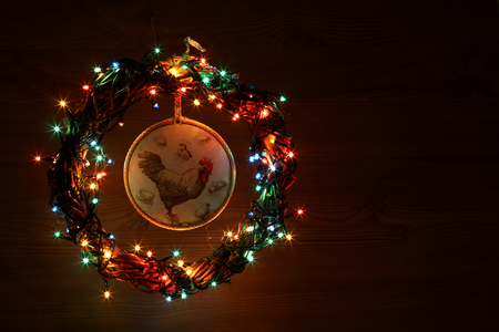 Happy New Year 2017 on the Chinese calendar of rooster template copyspace card with hand made craft roosters decoupage in decorated Christmas wreath and garlands of colored light. Wooden background.の写真素材