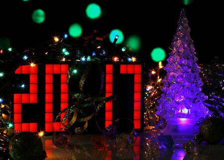 Happy New Year 2017 colorful greeting card real photo with blue glass Christmas tree on bokeh background. Party poster, banner or invitation. Mirror surface. Number formed from red digital clock.の写真素材