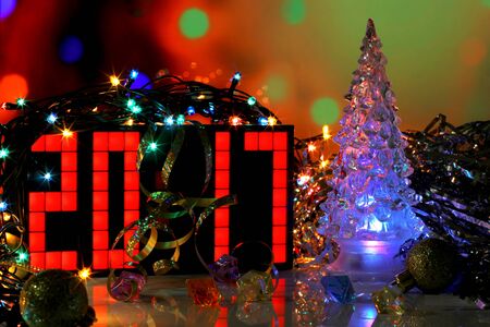Happy New Year 2017 colorful greeting card real photo with blue glass Christmas tree on dark red bokeh background. Lamp garland lights. Mirror surface. Number formed from red digital clock.の写真素材