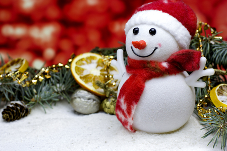 Christmas and New Year`s  red background with a toy snowman, dry oranges fruit, fir brunch, pin cone, walnut in snowの写真素材