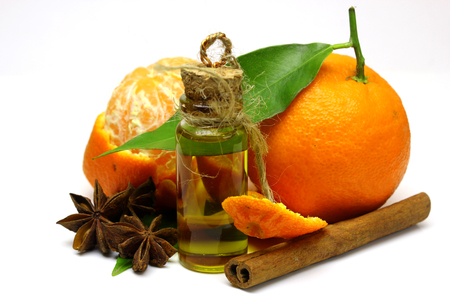 Mandarin, tangerine citrus fruit, with green leaf, isolated on white background. Cosmetic Essence, perfume oil natural plant product in a glass bottle. The aroma of cinnamon and star anise.の写真素材