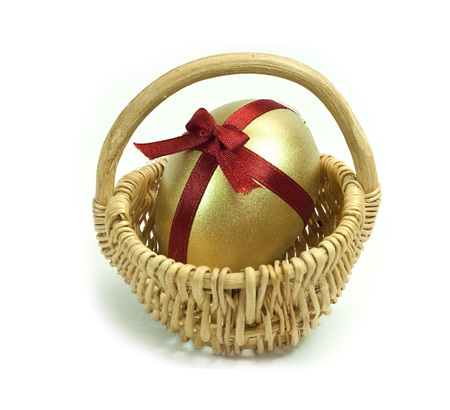 Easter Gold egg with red ribbon cross and bow in basket cart. White background isolated.の写真素材