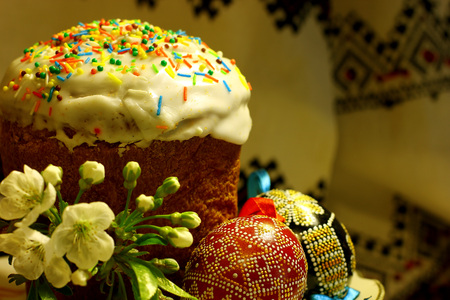 Easter bread and decorated eggs on the background traditional tablecloth towel. Spring of flowering...