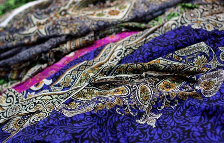 Crumpled and wrinkled blue fabric background. Oriental style bright gold pattern on a thin silk...